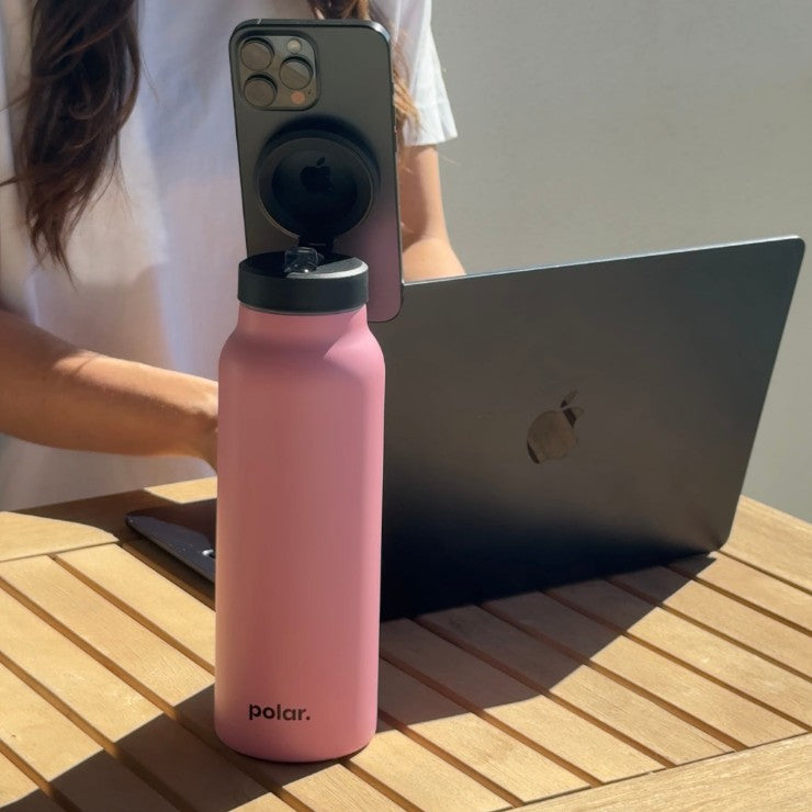 Pink magnetic water bottle phone stand used for hands-free video calls and working on a laptop