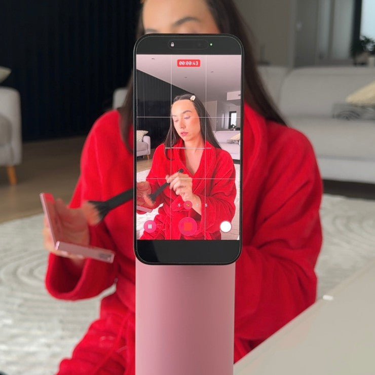 Pink magnetic water bottle phone mount used as a tripod for filming content and recording videos hands-free