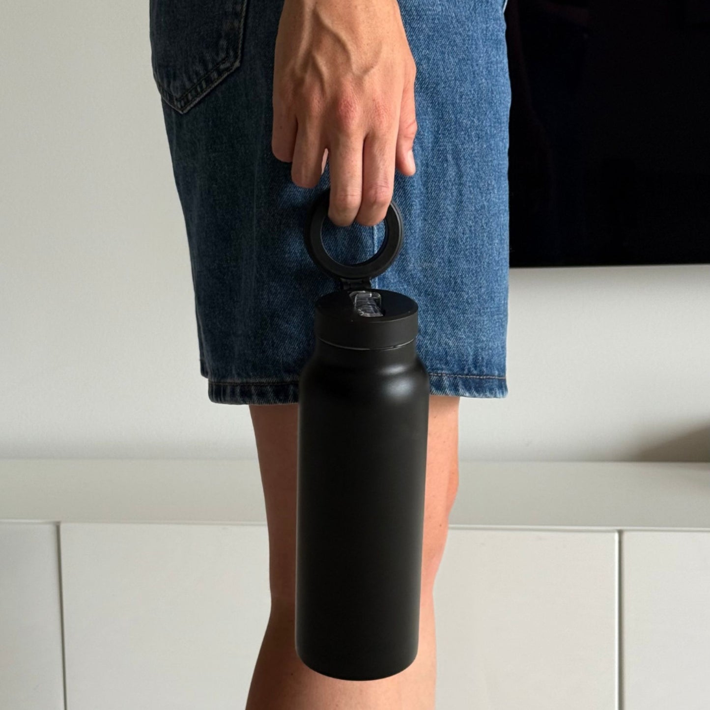 Carbon magnetic water bottle with phone holder used for hands-free workouts in a gym setting